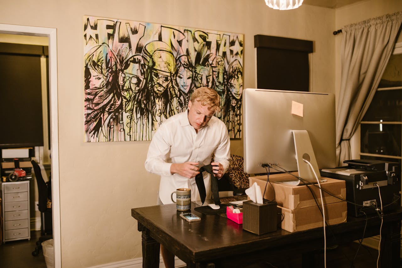A businessman adjusting his tie in a stylish home office, preparing for an online meeting.